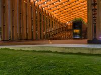 a wooden building with stairs and grass inside of it with lights on the top half