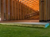 a wooden building with stairs and grass inside of it with lights on the top half