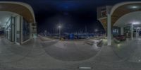 the panoramic view of an empty street at night of a busy city marina with a fire hydrant nearby