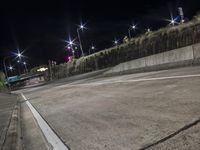 empty parking lot with no cars or pedestrians on it at night with light poles and road signs in front