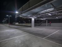 an empty parking lot at night with lights on the ceiling and overhead lighting over it