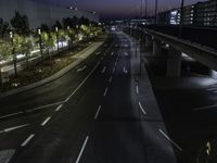 a city road with white lines at night, and traffic lights lit up along both sides