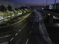 a city road with white lines at night, and traffic lights lit up along both sides