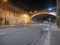 a road near a stone bridge in a large area with the lights on at night