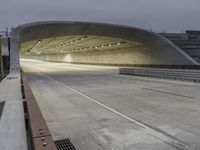 a concrete tunnel at night in the city, illuminated up by street lights and recessed on overhead