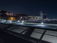 benches overlooking the night city skyline of a large city with skyscrapers behind them '