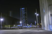 a city square at night with buildings in the background with lights coming on and people outside