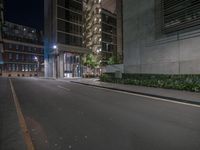 an empty street at night with buildings in the background at the corner of town and city