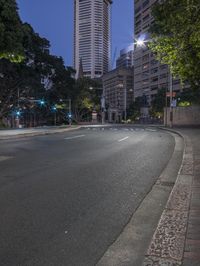 empty city street with buildings and traffic lights on both sides of it at night, during dusk