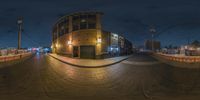 a fish eye view at night of the city street with lights on and buildings around