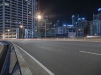 an empty city street at night with a bus lane and high rise buildings on both sides