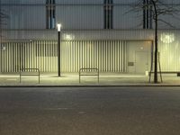 a paved street in the middle of buildings with tall windows at night, with car lights on