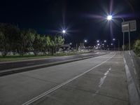 an empty road and street light at night, with a light pole in the background