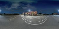 a city street at night with an empty parking lot and street lights in the background