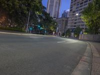 a man is riding a skateboard on a city street at night with city buildings and trees