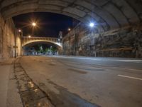 an empty street is pictured at night time under a bridge which runs under the highway