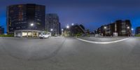 a photo of an urban street intersection at night, shot from fish eye lens with a camera