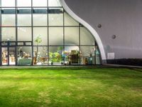 the glass building has a garden inside of it and is illuminated by lights, from inside