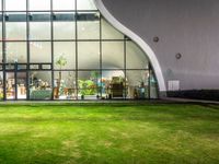 the glass building has a garden inside of it and is illuminated by lights, from inside