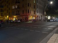 a road at night in front of an apartment building on a street corner, with police tape running beside the road