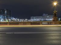 a city street next to a large bridge lit up at night by buildings and lights