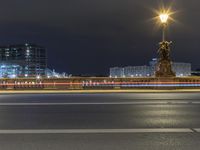 a city street next to a large bridge lit up at night by buildings and lights