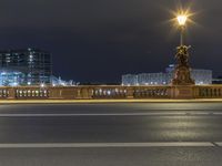 a city street next to a large bridge lit up at night by buildings and lights