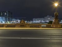 a city street next to a large bridge lit up at night by buildings and lights