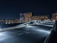 a bridge that goes across an empty road over a river at night at a marina