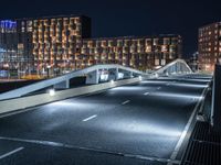 a bridge that goes across an empty road over a river at night at a marina