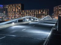 a bridge that goes across an empty road over a river at night at a marina