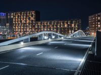 a bridge that goes across an empty road over a river at night at a marina