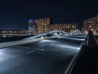 a bridge that goes across an empty road over a river at night at a marina