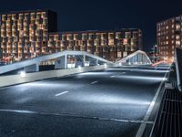 a bridge that goes across an empty road over a river at night at a marina