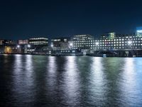 there are three buildings next to the water at night in this city setting on the river