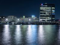 there are three buildings next to the water at night in this city setting on the river