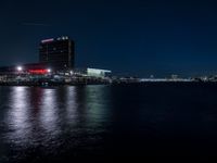 there are three buildings next to the water at night in this city setting on the river