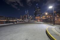 an empty, empty road leads to a city at night with buildings lit up in the distance