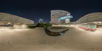 a 360 - angle image of a large building at night with a ramp and chair set in front of it