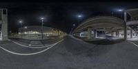 a wide angle panoramic shot shows empty road under bridge at night time,