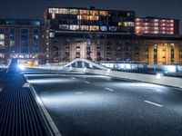 a bridge over a city street at night near a building and a bus stop area