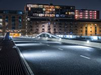 a bridge over a city street at night near a building and a bus stop area