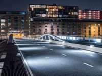 a bridge over a city street at night near a building and a bus stop area