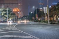 a city street with buildings and neon lights at night time in hong china as seen from an empty city highway