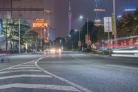 a city street with buildings and neon lights at night time in hong china as seen from an empty city highway