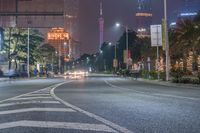 a city street with buildings and neon lights at night time in hong china as seen from an empty city highway