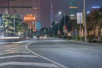 a city street with buildings and neon lights at night time in hong china as seen from an empty city highway