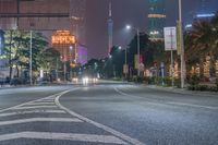 a city street with buildings and neon lights at night time in hong china as seen from an empty city highway