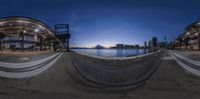 the 360 view shows people on the shore at night in the distance are a clock and water