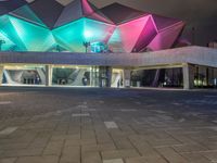 a building with three blue, white and purple lights on the side of it that appears to be an auditorium